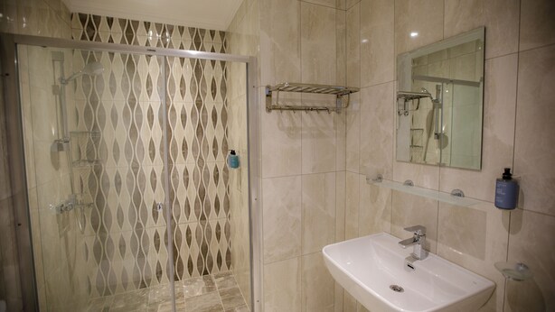 Un baño con cabina de ducha de vidrio, un lavabo y un espejo.