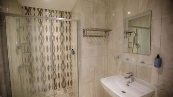 Un baño con cabina de ducha de vidrio, un lavabo y un espejo.