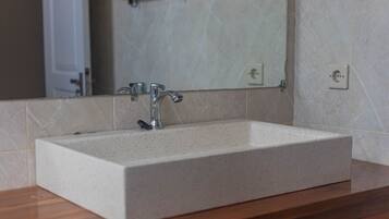Un baño con un lavabo rectangular, un espejo y una encimera de madera.