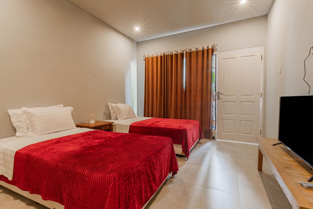 A hotel room with two beds, a TV, and a door.