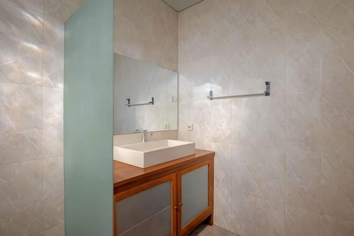 A bathroom with a wooden vanity, a large mirror, and a towel rack on the wall.