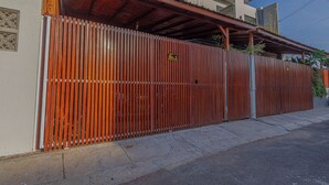 Una propiedad cercada con valla metálica, acceso cubierto y un edificio con techo de tejas.