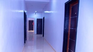 A hallway with a shiny tiled floor, doors on both sides, and a light fixture on the ceiling. - Westbro hotel and suites  (Lekki)
