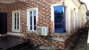 A building with a brick facade, large windows, and a small outdoor area with steps leading to a door. - Westbro hotel and suites  (Lekki)