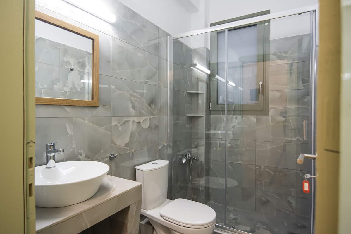 A bathroom with a marble sink, toilet, and glass shower enclosure.