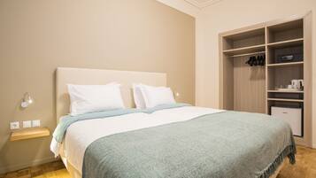 A neatly made bed with a white headboard, a light blue throw blanket, and a wooden nightstand with a lamp.