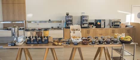 A breakfast buffet with various food items and a coffee station in a modern kitchen setting.