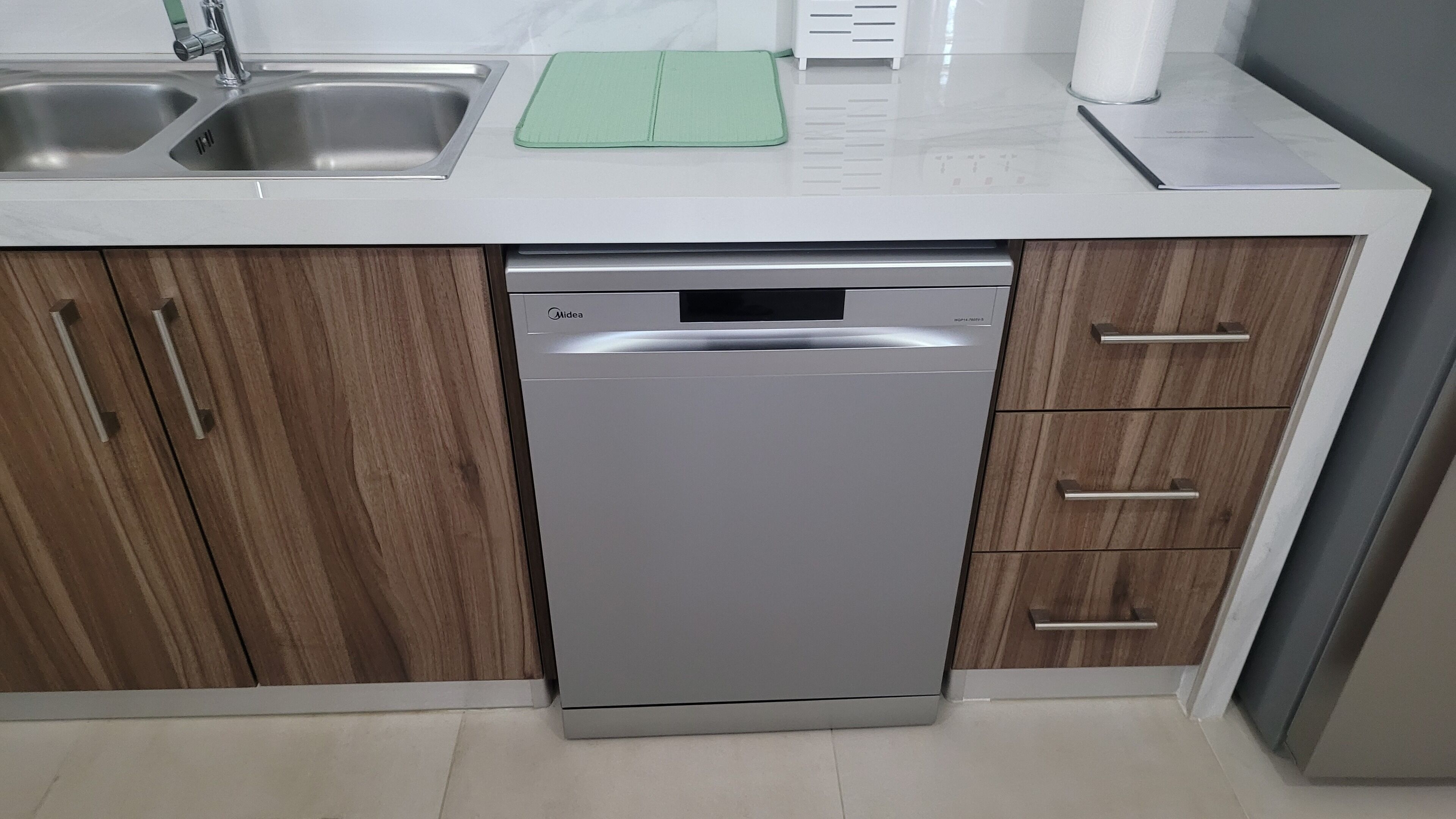 A modern kitchen with a dishwasher, wooden cabinets, and a stainless steel sink.