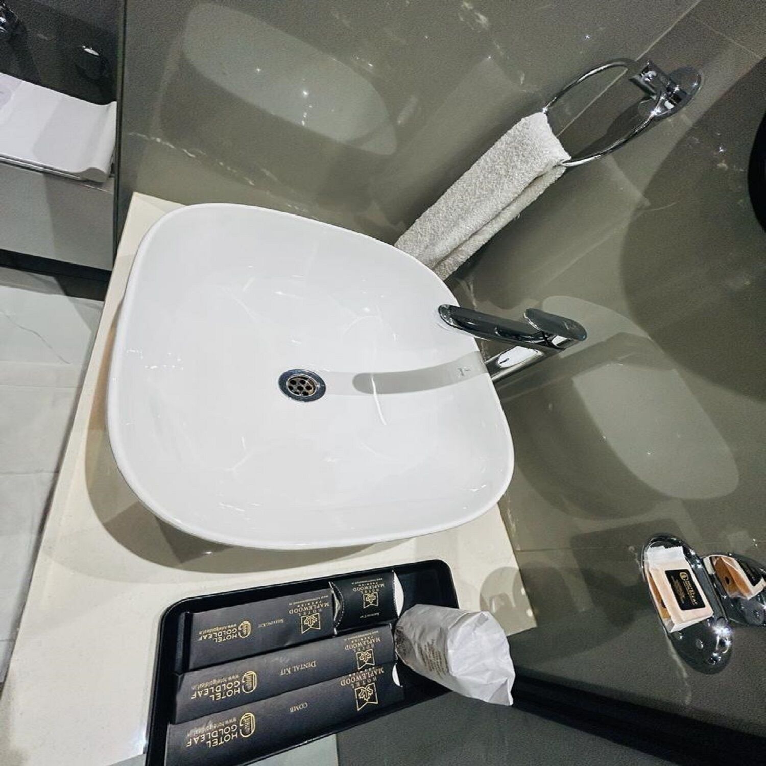 A bathroom with a white sink, a towel rack, and a tray with toiletries.