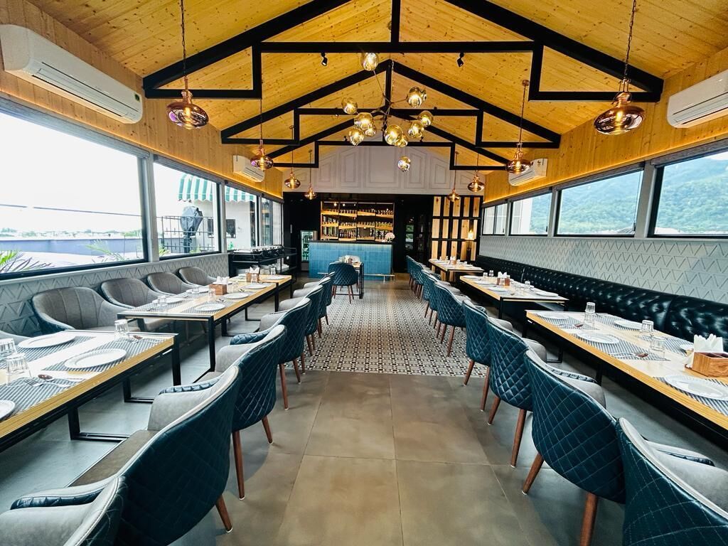 A restaurant with a long communal table, individual booths, and a bar area.