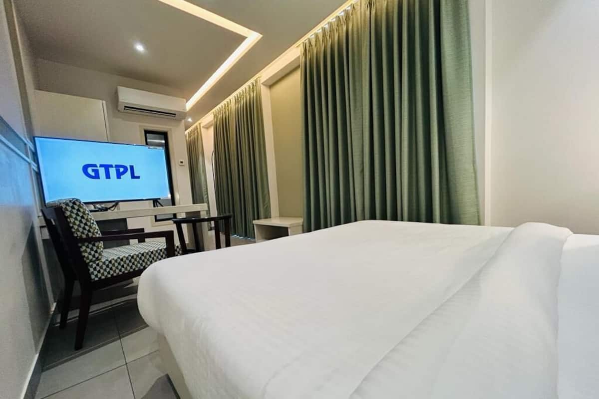 Une chambre d’hôtel équipée d’un lit, d’un bureau avec un ordinateur et d’un téléviseur affichant « GTPL ».