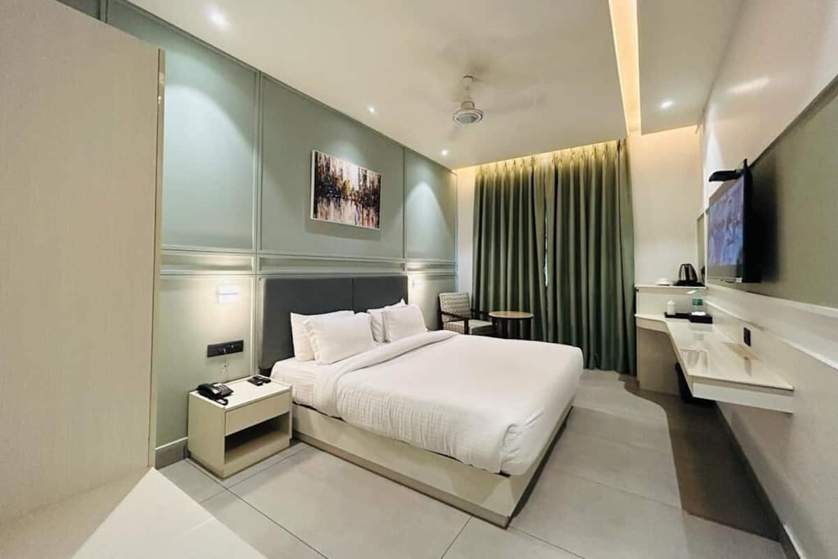 Une chambre d’hôtel moderne dotée d’un grand lit, de tables de chevet, d’un téléviseur à écran plat et d’un petit bureau.
