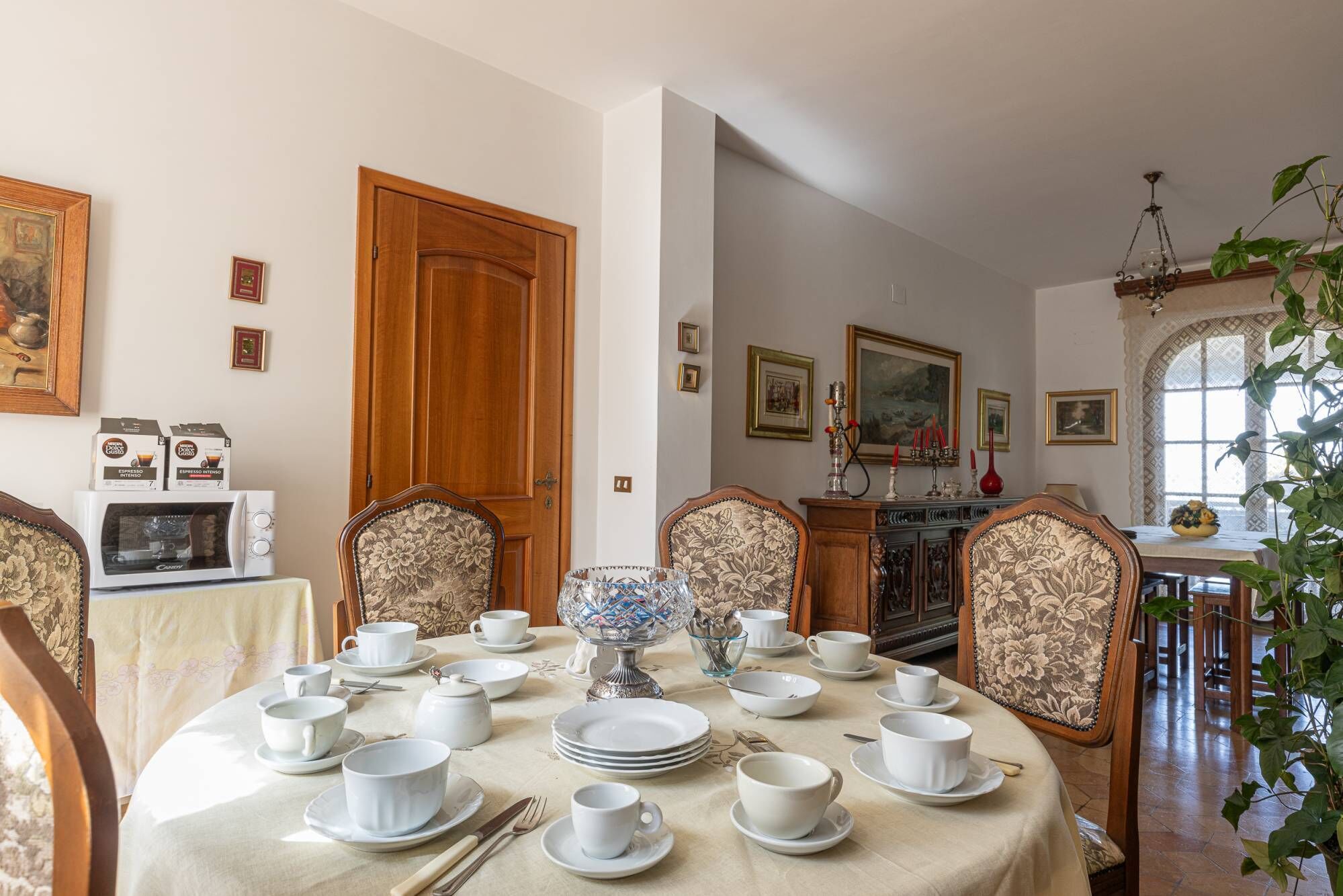 Une salle à manger avec une table ronde dressée pour le repas, entourée de chaises ornées de motifs floraux.