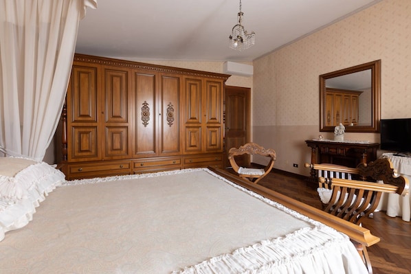 A spacious bedroom with a large bed, wooden wardrobe, and a vanity with a mirror. - B&B Villa dei Desideri (Chieti)