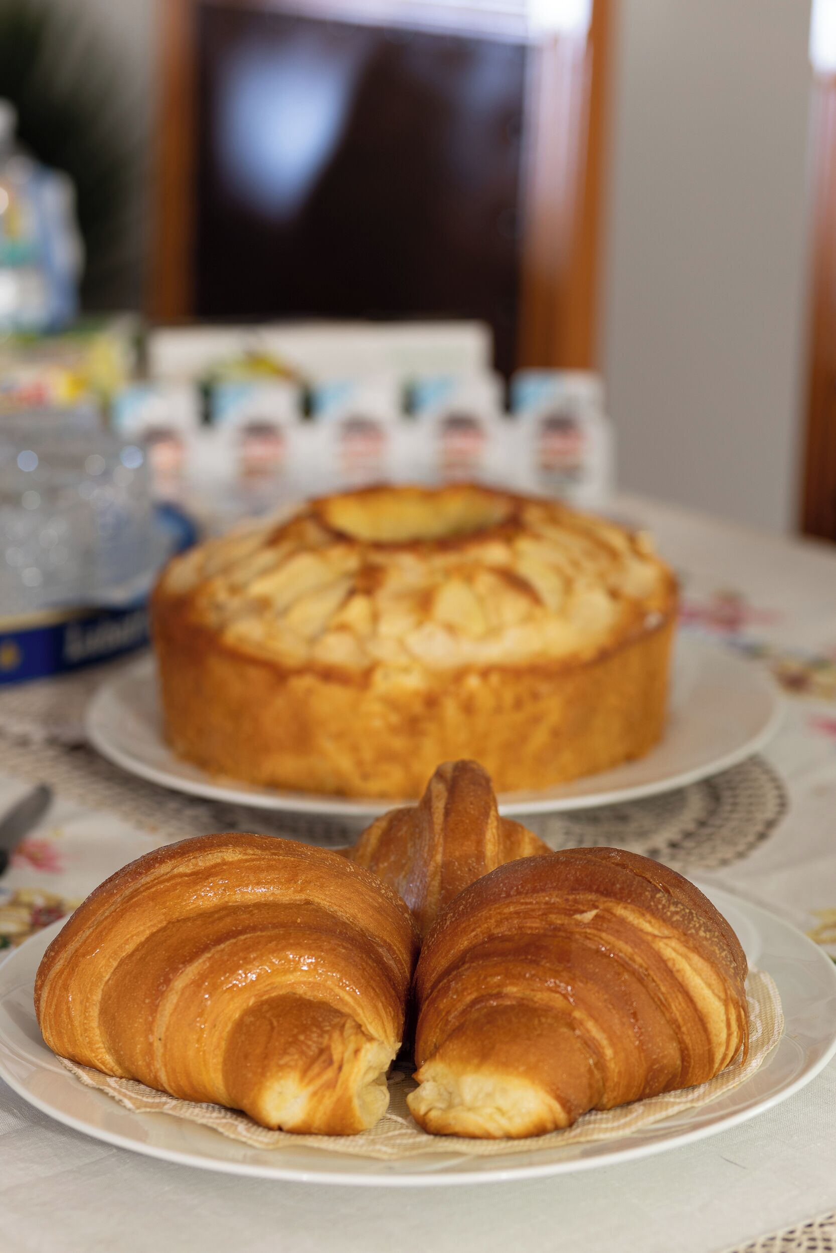 Una mesa con un pastel y dos cruasanes en platos.