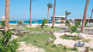 A resort with a pool area surrounded by palm trees and a view of the ocean. - White Valley Palace  (Hurghada)