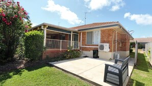 A two-story house with a covered porch, a brick exterior, and a small front yard. - Unit 35 Lakeview Park Bargara (Bargara)
