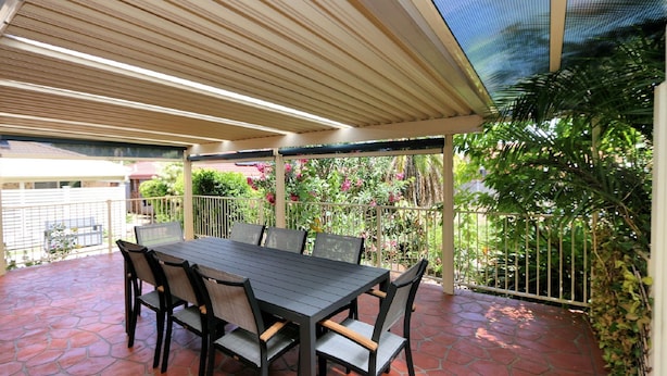A covered patio with a table and chairs, surrounded by a fence and greenery. - Unit 35 Lakeview Park Bargara (Bargara)