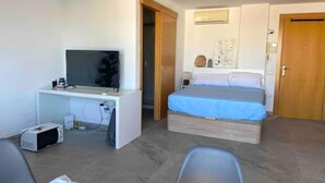 Een slaapkamer met een bed, een bureau met een televisie, een stoel en een klein tafeltje.