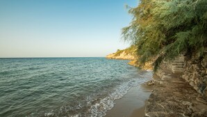 A coastal scene with a rocky shoreline, calm sea, and a clear sky.