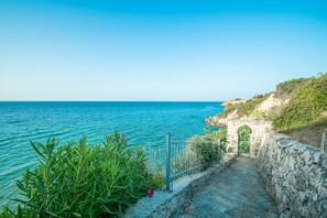 A coastal path leading to a stone archway overlooking the sea.