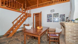 A wooden staircase leading to an upper level, a dining area with a table and chairs, and a brick fireplace.