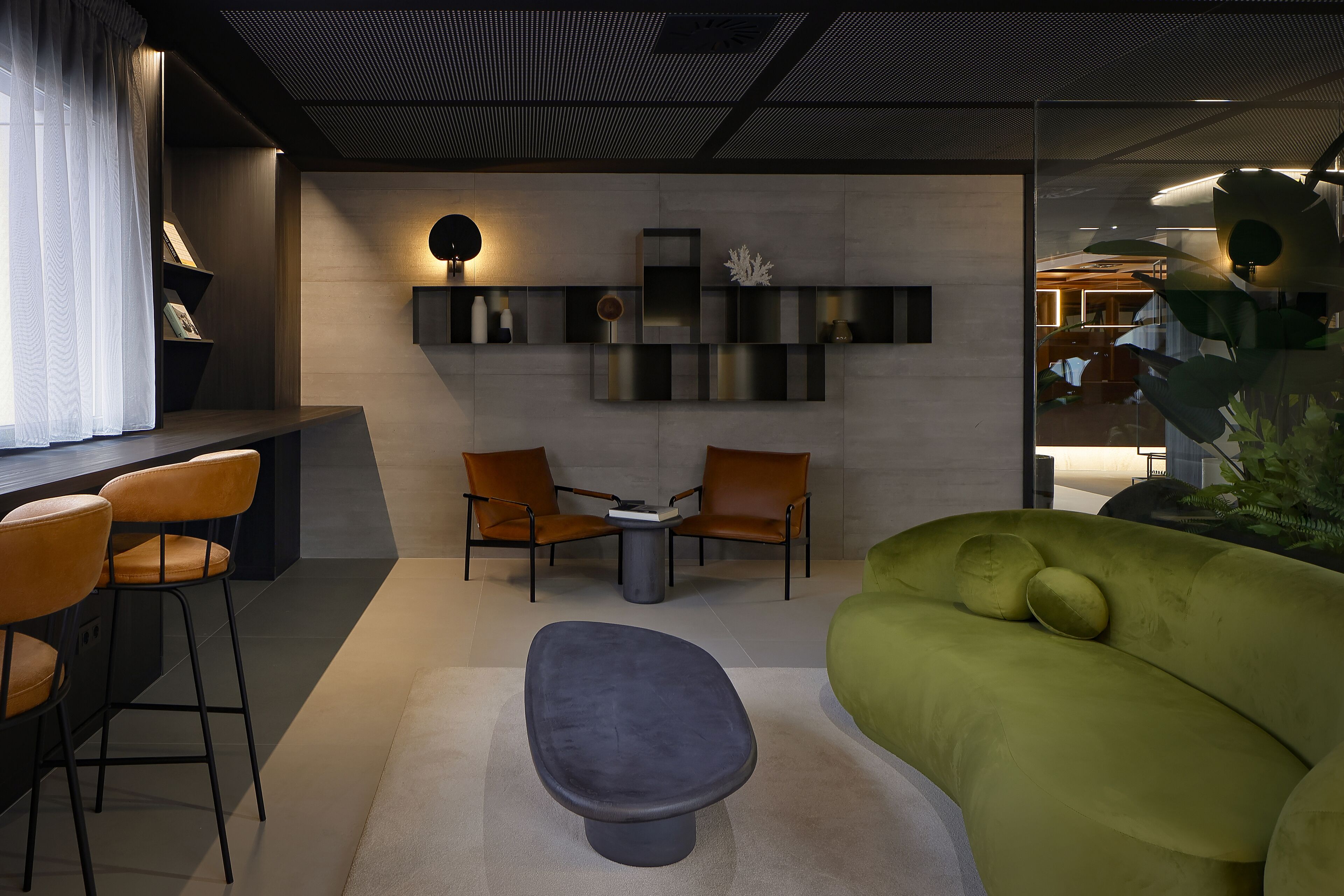Un interior moderno con una zona de bar, asientos y un sofá verde.