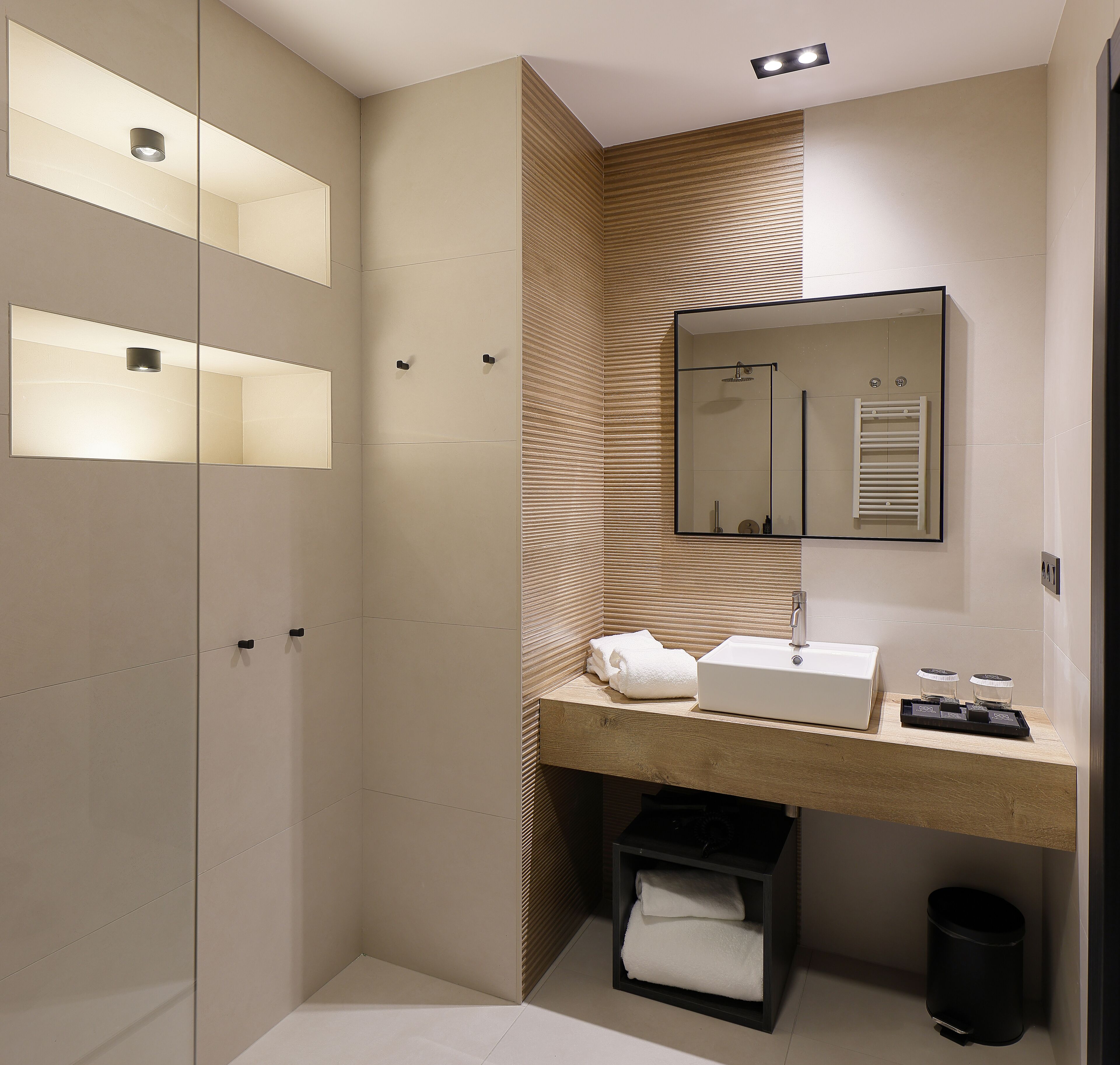 A modern bathroom with a large mirror, a sink, and a shower area.