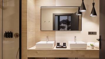 Une salle de bain moderne avec une douche à l’italienne, deux vasques, un miroir, des luminaires suspendus et un porte-serviettes.