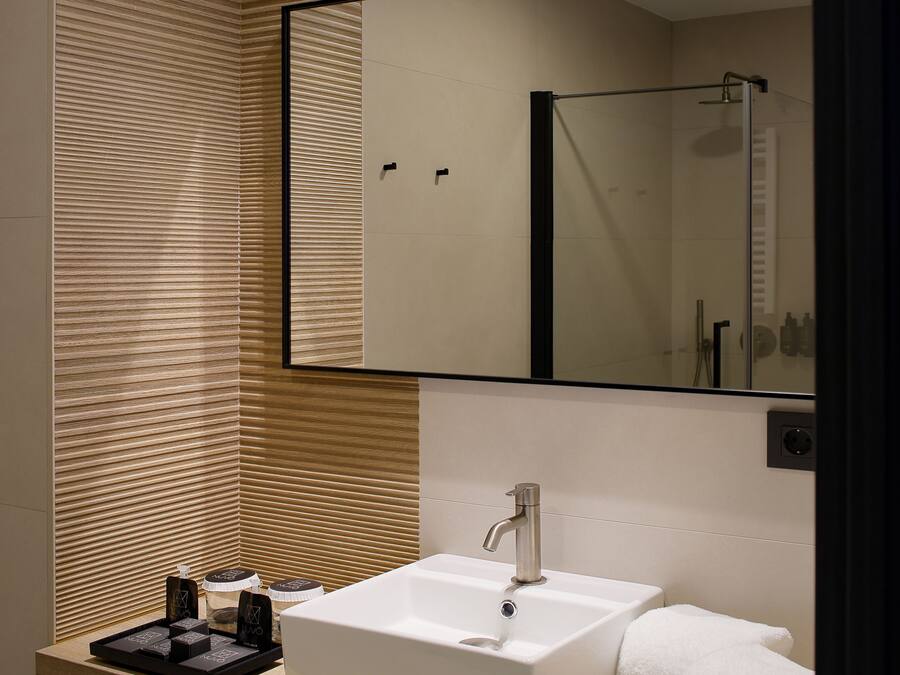 A modern bathroom with a large mirror, a white sink, and a towel.