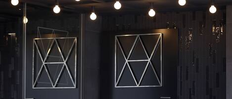 Un interior moderno con diseños geométricos en la pared y lámparas esféricas colgantes.
