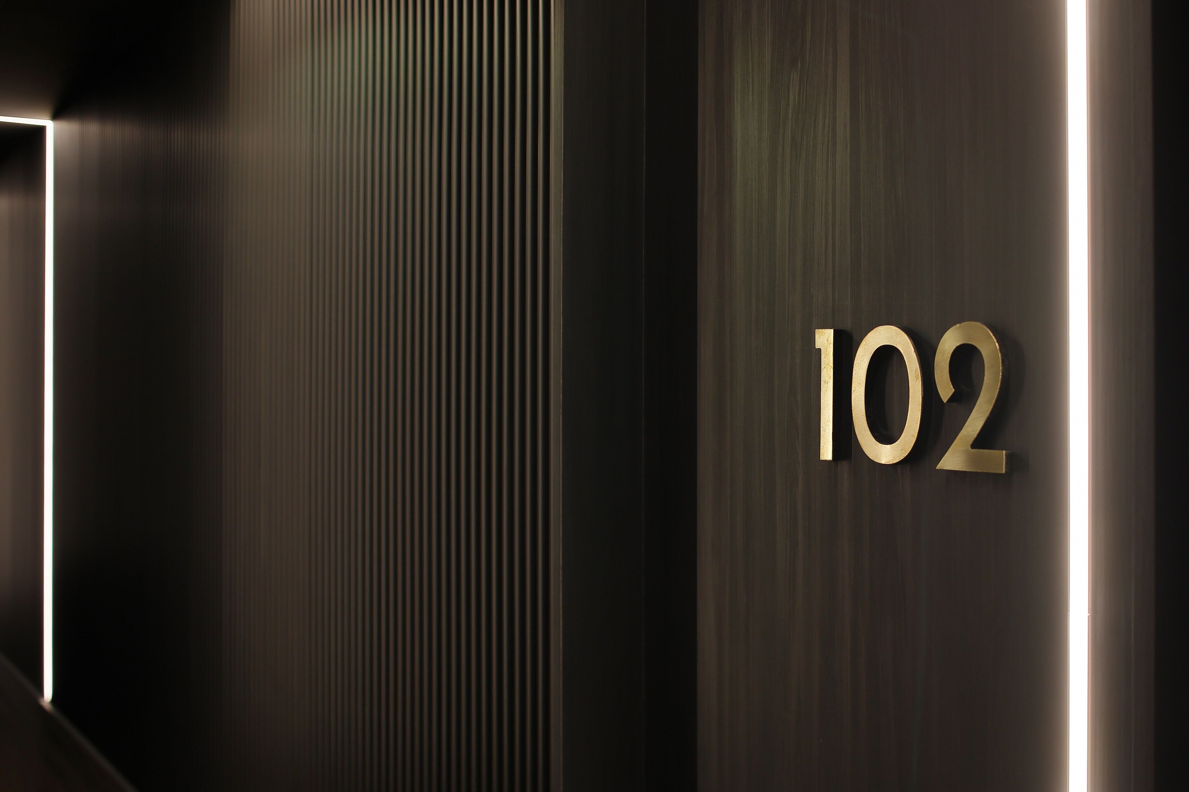 Un couloir moderne avec une plaque portant le numéro « 102 », en métal.
