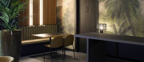 Un interior moderno con zona de comedor, una planta grande en maceta y un mural de palmeras.