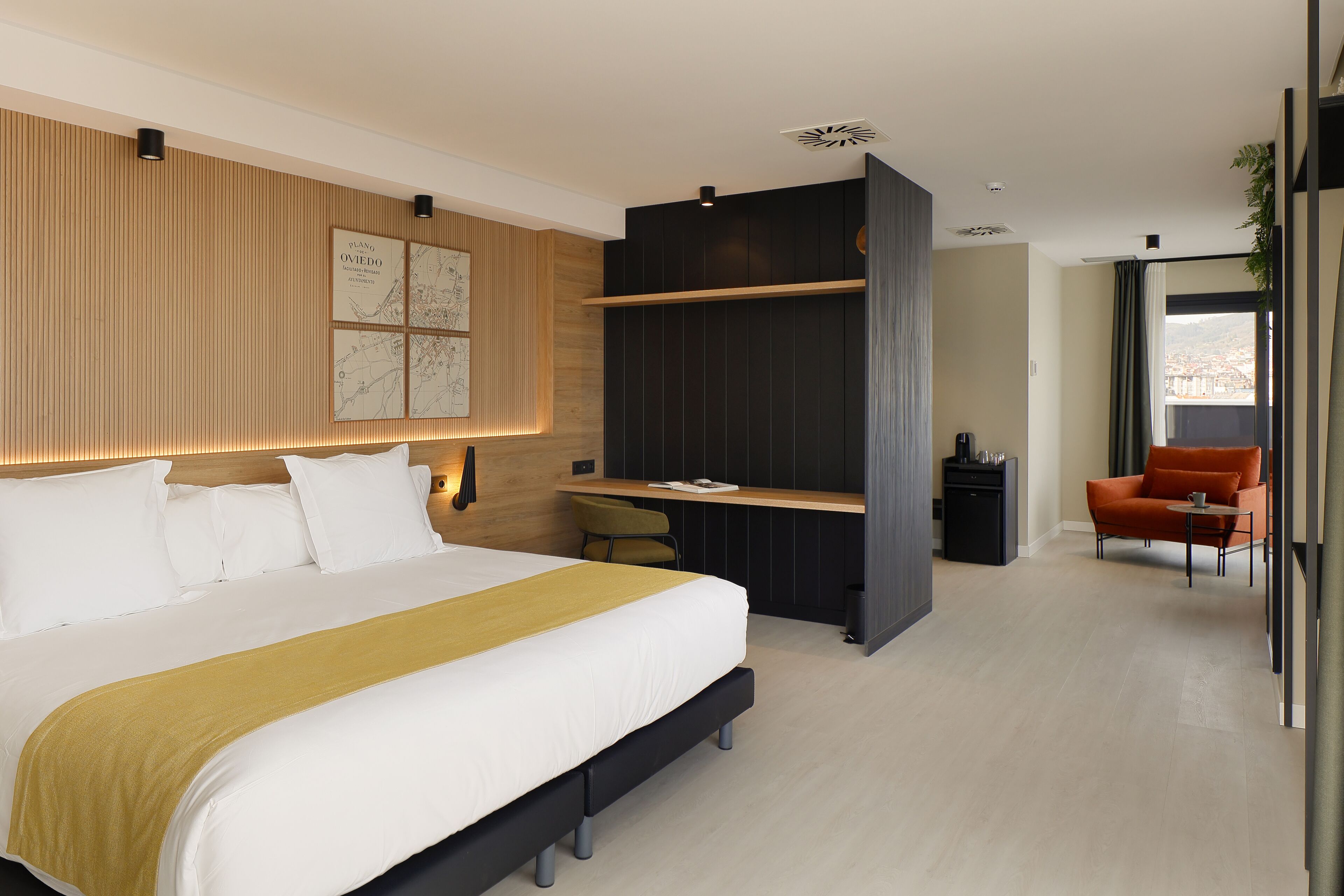 A modern hotel room with a large bed, a desk, and a seating area.