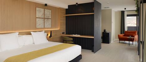 A modern hotel room with a large bed, a desk, and a seating area.