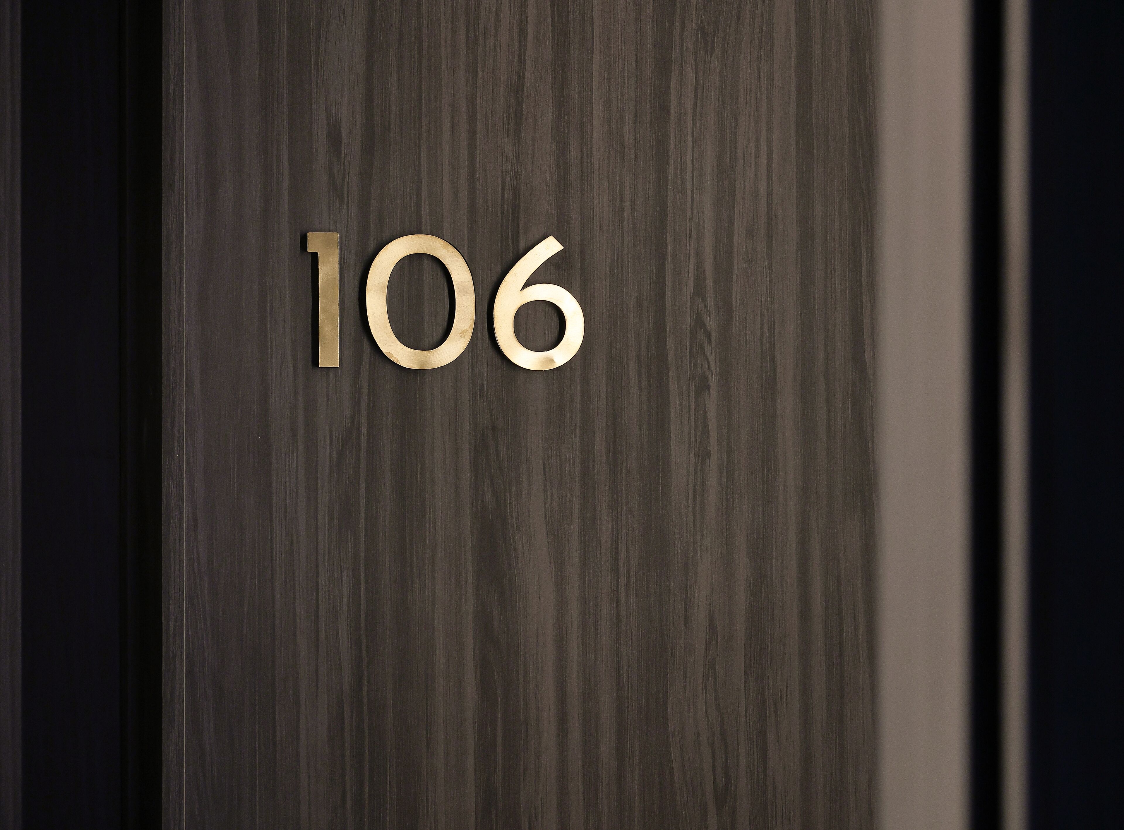 A dark wood door with a brass number '106' indicating a room or unit number.