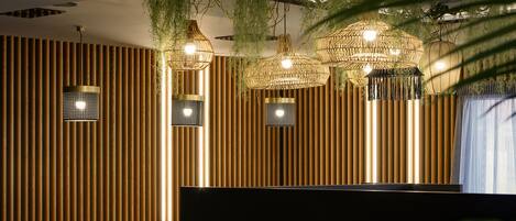 A modern interior with vertical wooden slats, hanging wicker lamps, and a dark partition.