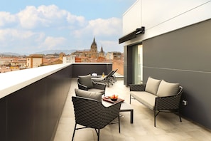 A balcony with outdoor seating, a view of a cathedral, and a cityscape in the background. - NUVÓ HOTEL BOUTIQUE (Oviedo)