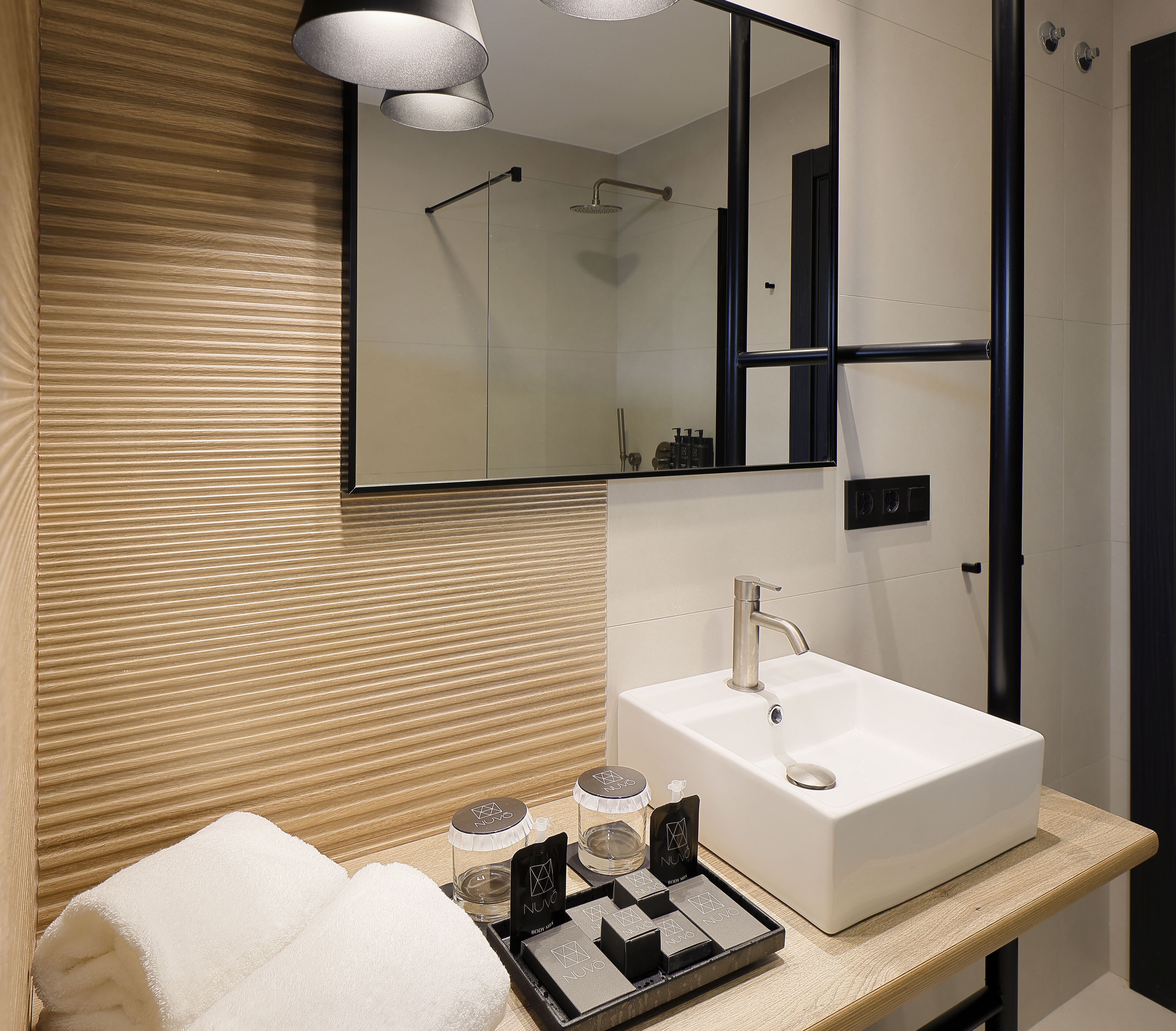Un baño moderno con un lavabo blanco, un espejo y una ducha.