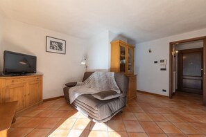 Un saló amb un sofà, una televisió, un armari i una porta.