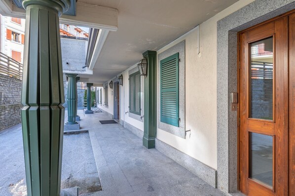A covered outdoor corridor with green shutters, a wooden door, and a stone wall. - SmartStay René Payot - Chamonix-Mont-Blanc (Chamonix-Mont-Blanc)