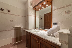 A bathroom with a marble sink, wooden cabinets, a towel rack, and a mirror with lights. - SmartStay René Payot - Chamonix-Mont-Blanc (Chamonix-Mont-Blanc)