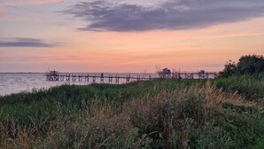 A pier extending into a body of water, surrounded by grassy areas. - Gîte Padura - Location 3 Chambres - Braud et Saint Louis (Braud-et-Saint-Louis)