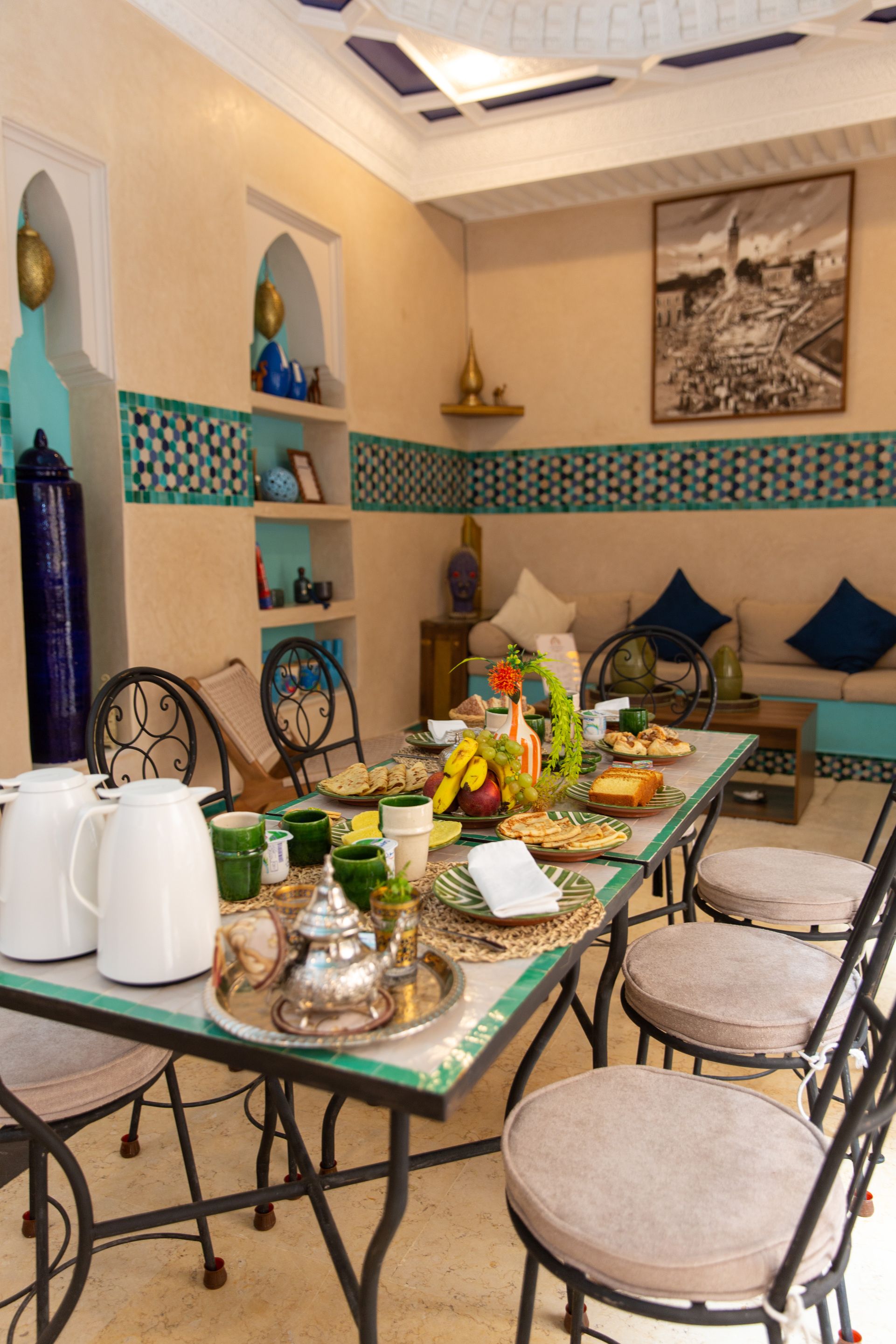A dining area with a long table set for a meal, chairs, a sofa, and decorative items.