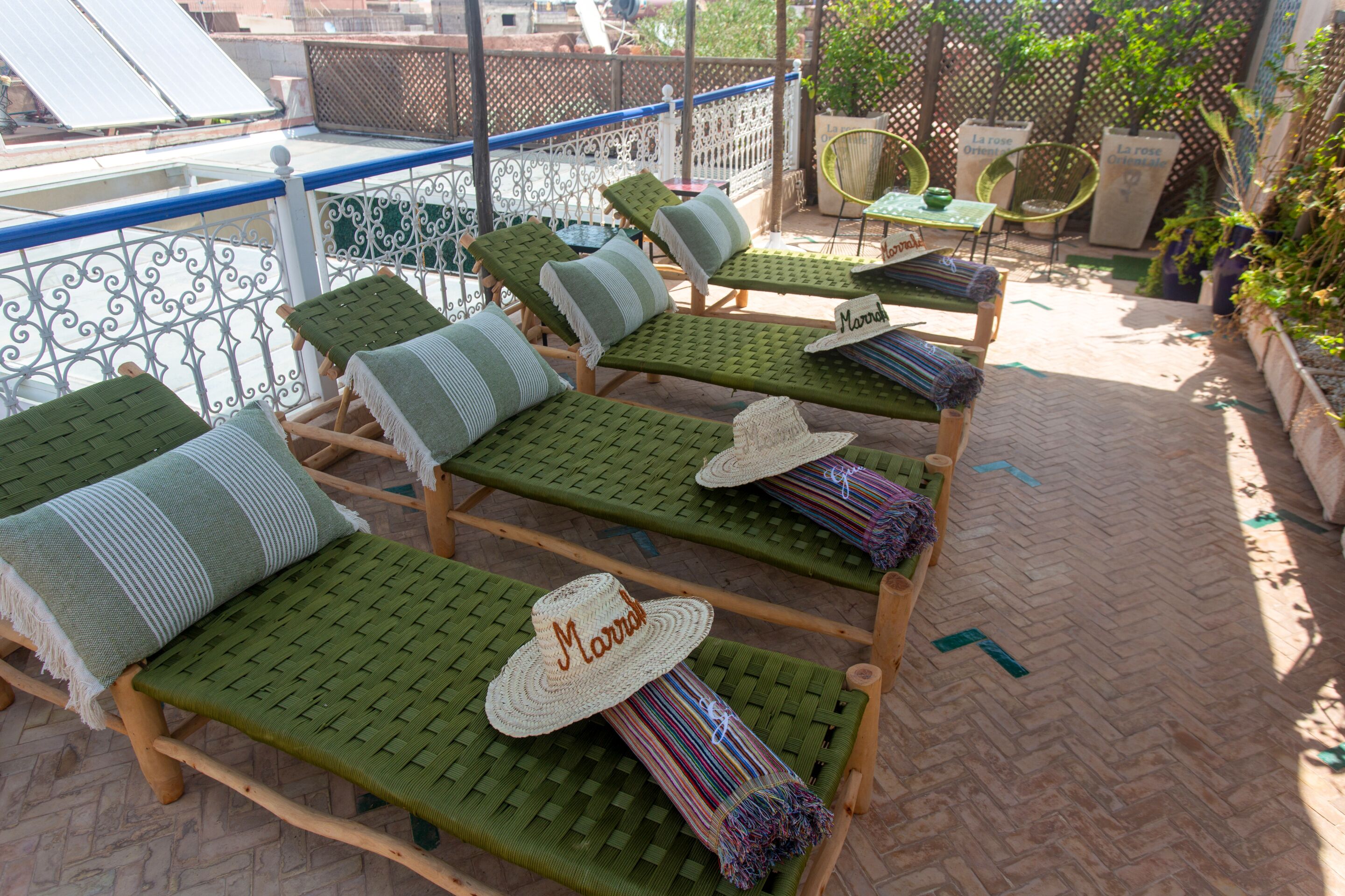 A rooftop terrace with multiple lounge chairs, each with a woven seat and backrest, and a hat placed on one of the chairs.