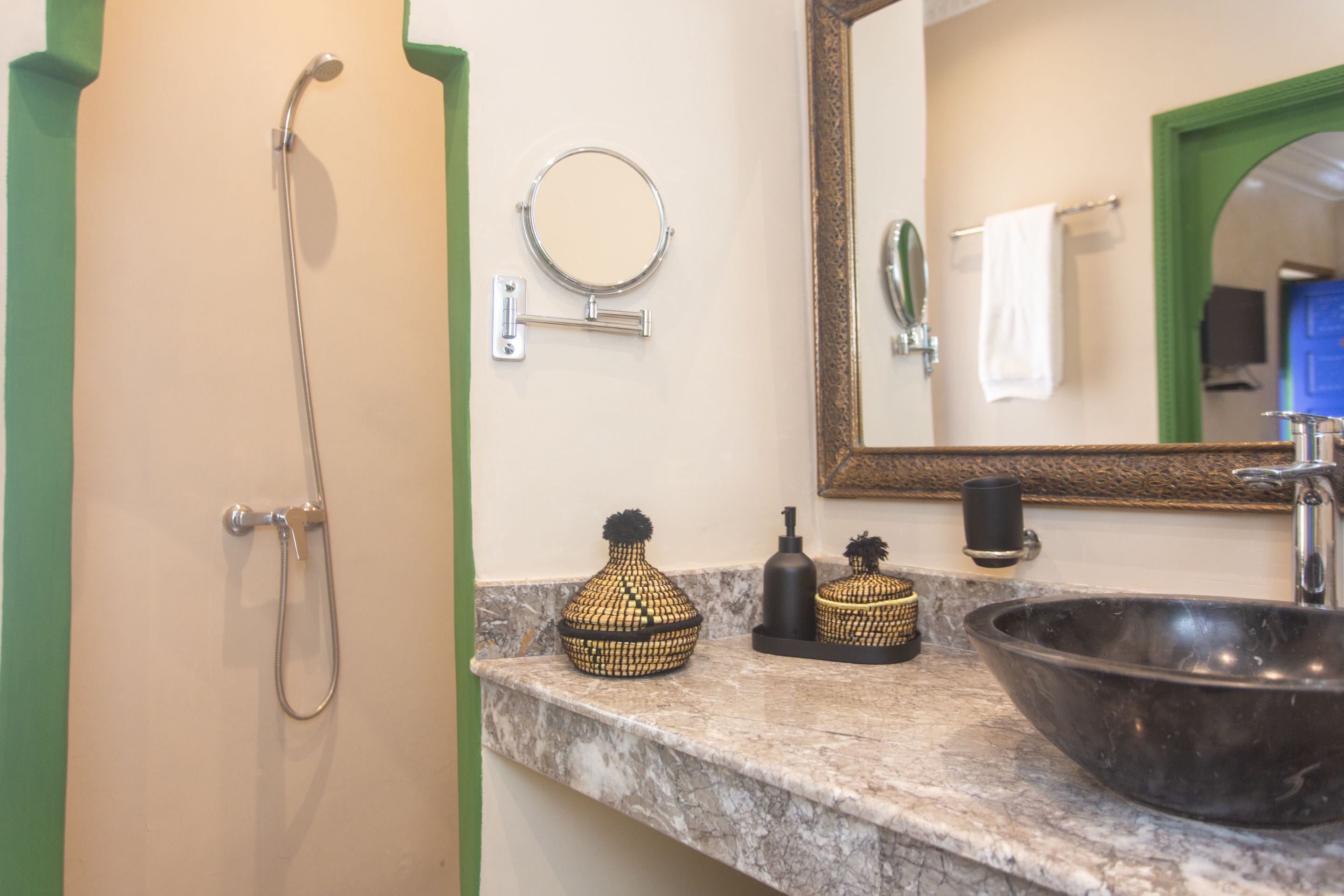 Une salle de bain équipée d’une douche, d’un lavabo, d’un miroir et d’objets décoratifs disposés sur le comptoir.