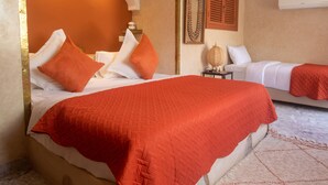 Una habitación de hotel con una cama grande, una cama más pequeña y una mesita de noche con una lámpara.