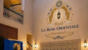A spa area with a pool, a decorative wall with the name 'Riad La Rose Orientale Marrakech,' and a blue door.