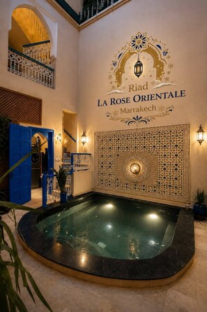 A spa area with a pool, a decorative wall with the name 'Riad La Rose Orientale Marrakech,' and a blue door. - Riad La Rose Orientale Marrakech (Marrakech)