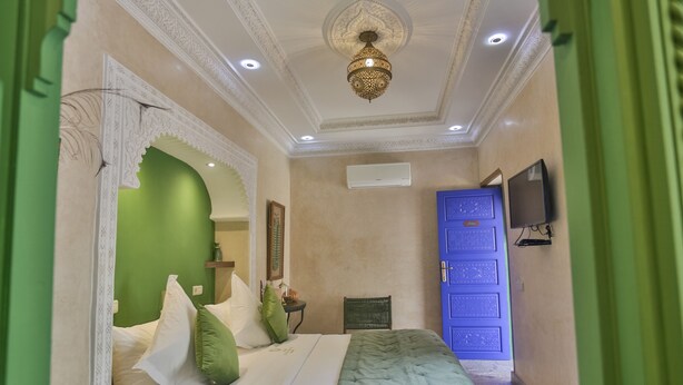 Un dormitorio con cama, un armario azul, televisión y un techo decorativo.